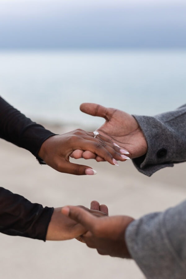 two sets of hands are holding in front of a dark cloudy sky at the lakefront
