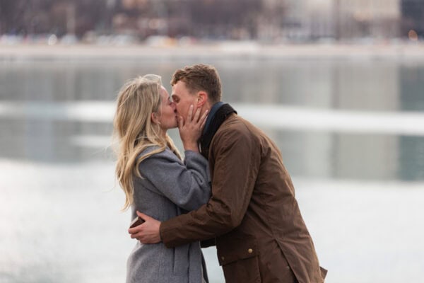 Newly engaged couple kisses beside Lake Michigan during a Chicago engagement photo session