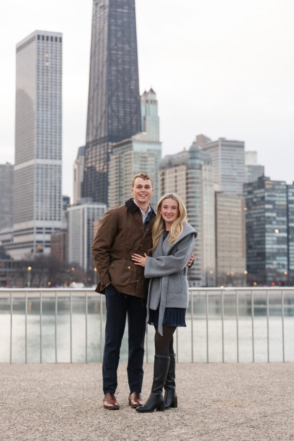 Newly engaged couple poses together at Olive Park with Chicago's skyline in the background.