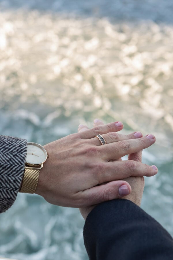 Close-up of hands intertwined with engagement ring , lake water softly blurred in background after a Chicago proposal