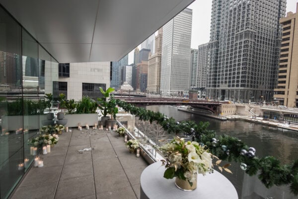 The RPM Seafood terrace on the chicago river is decorated for a Surprise proposal with winter snow, candles and white rose arrangements.