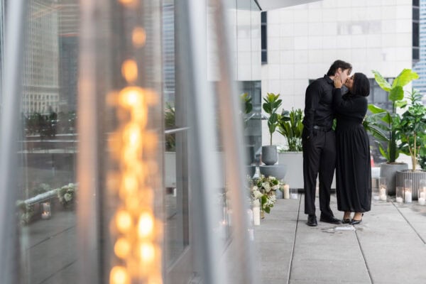 a man and his girlfriend share a kiss just moments after he proposed to her as they stand on the RPM terrace on the chicago river