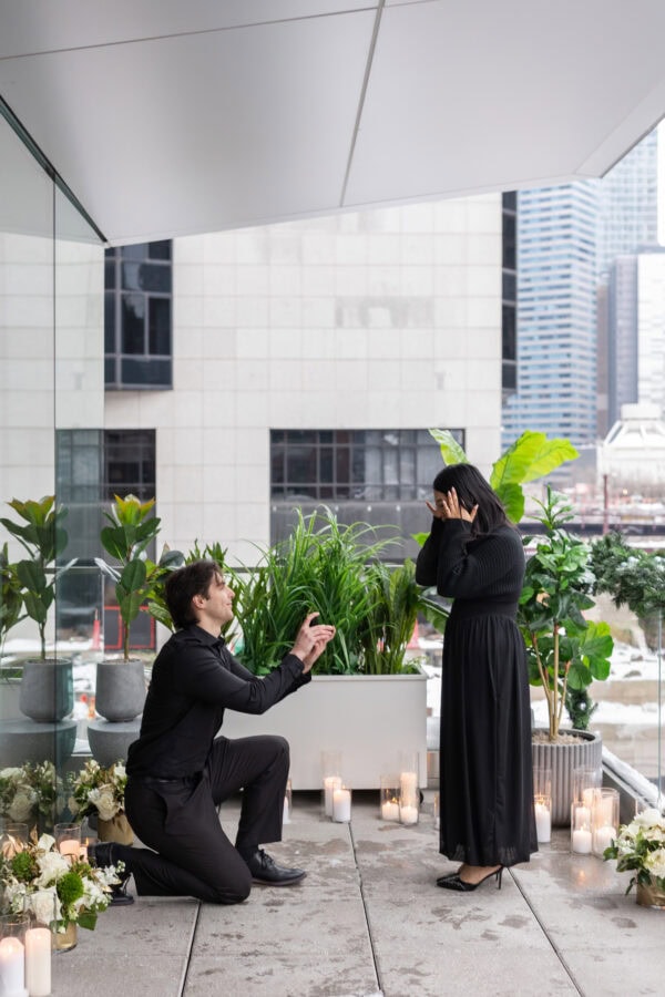 a man goes down on one knee as he proposes to his girlfriend on the terrace of RPM seafood on the chicago river.