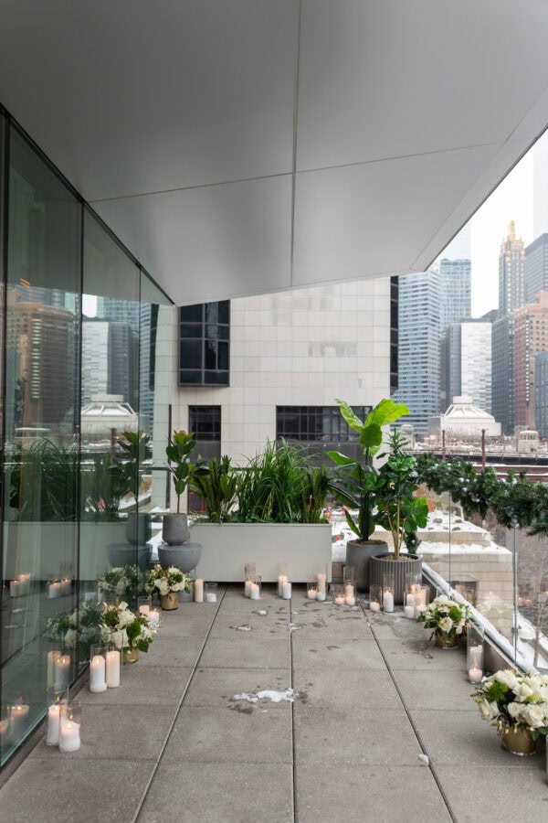 The RPM Seafood terrace on the chicago river is decorated for a Surprise proposal with winter snow, candles and white rose arrangements.