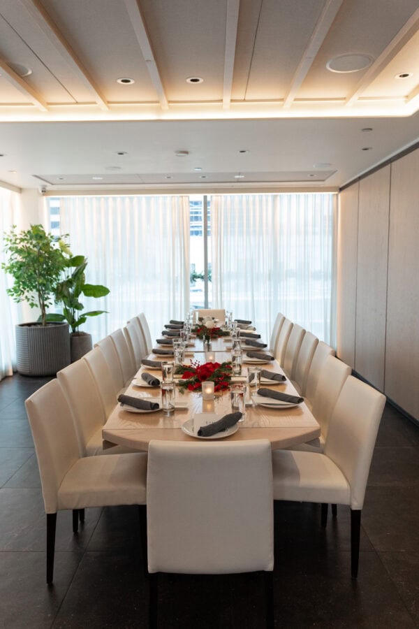 a private all white holiday dinner table is set with red roses and christmas greenery at RPM seafood in Chicago