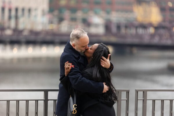 a couple shares a kiss after just getting engaged on the Chicago River