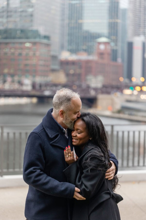 a newly engaged couple shares a hug just moments after he proposed on the chicago river