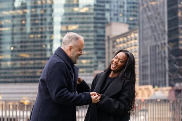 a couple celebrates with laughter just moments after getting engaged on the chicago river