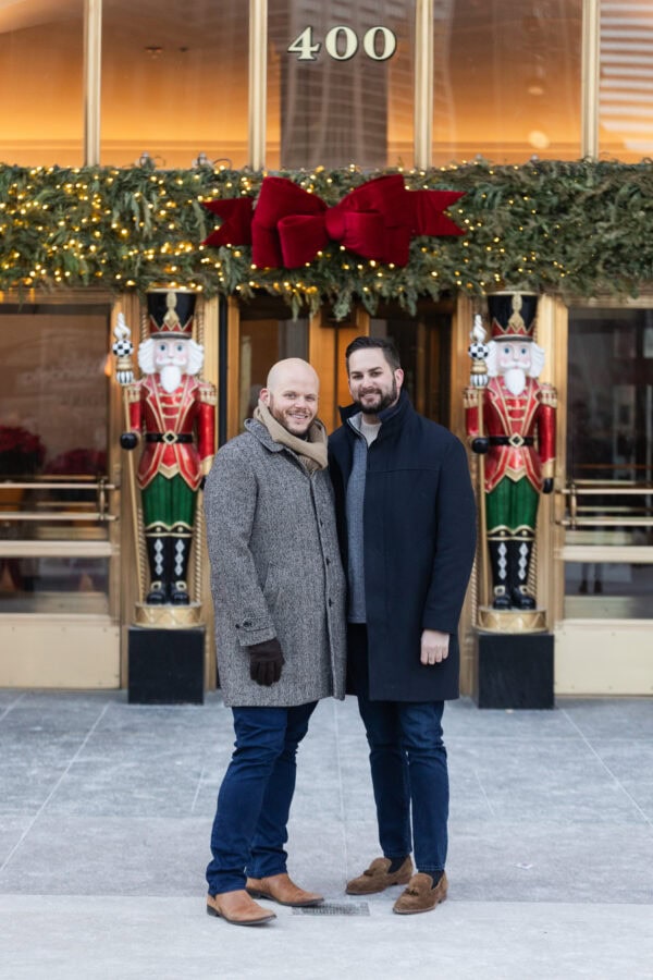 A same sex couple poses for an engagement photo at the Wrigley Building in Chicago with Christmas Decor